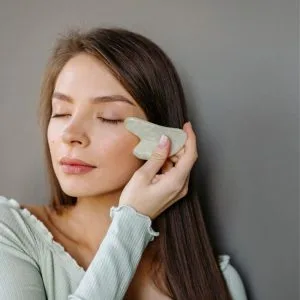 Kobieta wykonuje masaż twarzy kamieniem GUA SHA – kurs online