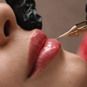 Makijaż permanentny ust – zbliżenie na usta i igłę podczas zabiegu