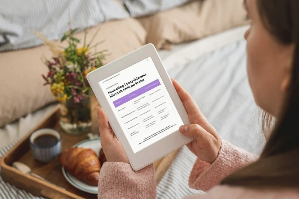 Kobieta czyta e-book „Jak zarabiać w branży beauty” na tablecie – rozdział o marketingu i pozyskiwaniu klientek krok po kroku.